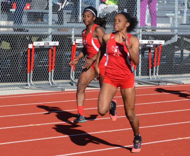 Alton's LaJarvia Brown blazed a 12.0 time in the 100 meters on Monday. Shown with her is freshman Jeanea Epps. (Photo by Dan Brannan)