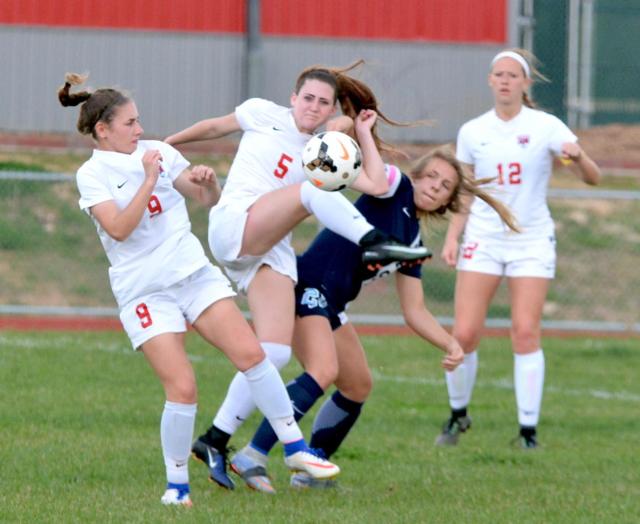 The Redbirds' No. 5 Sydney Schmidt battles for the ball with No. 9 Taylor Imming and No. 12 Lexi Schrimpf Monday night at Alton High against Belleville East. (Photo by Dan Brannan)